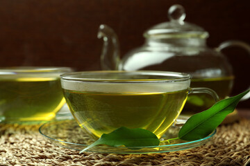 Fresh green tea in glass cups, leaves and teapot on table, closeup