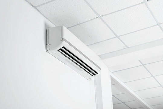 Modern air conditioner on white wall indoors, low angle view