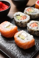 Delicious sushi rolls on black plate, closeup