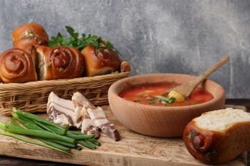 Delicious pampushky (buns with garlic) and salo served for borsch on wooden board, closeup. Traditional Ukrainian cuisine