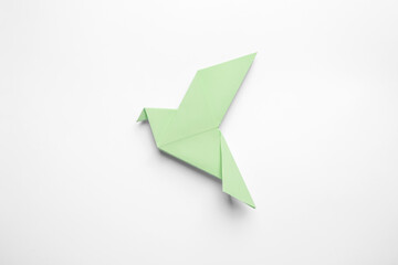 Fototapeta premium Beautiful light green origami bird on white background, top view