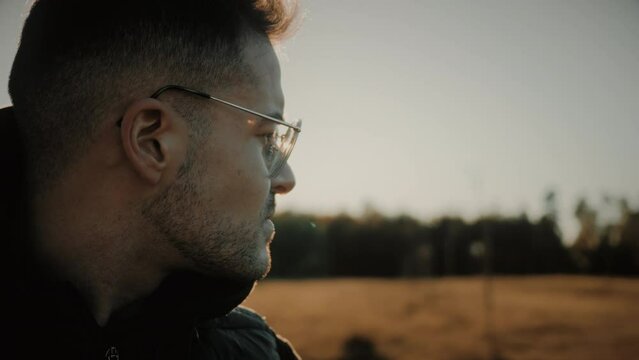 Close-up on face. Caucasian man feeling lost in life suffering from depression, anxiety, solitude, sadness, negative thinking, stress, unhappiness. Side view of thoughtful male out in nature at sunset