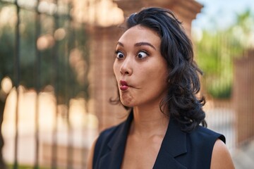 Young beautiful hispanic woman smiling confident doing funny gesture with lips at street