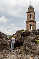 Iglesia, rocas volcánicas y caminante. Pueblo en ruinas, Parangaricutirimicuaro, Michoacán, México.