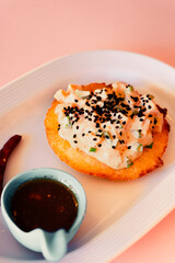 Asian food with sauce on a plate on pink background.