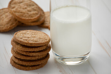Oatmeal cookies and a glass of milk on a white wooden background.