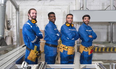 Group of technician in blue mechanic jumpsuit, ear muff and yellow tool belts stand with arms...