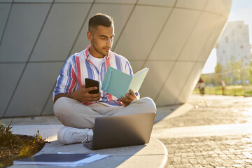 Pensive middle eastern student studying, exam preparation, reading book in university campus....