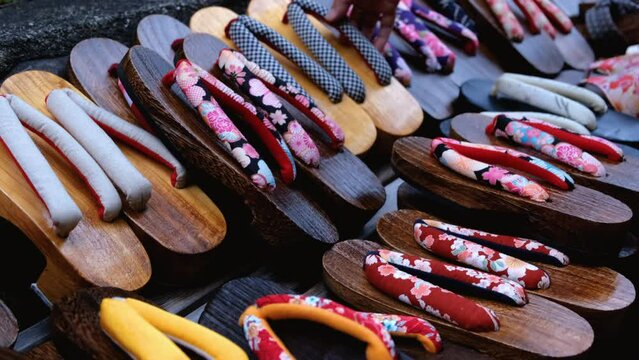 Geta traditional Japanese wooden footwear in store. Female hand choosing shoes at store.
