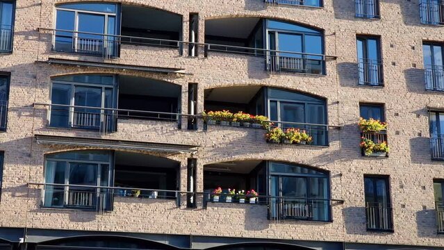 Apartment building with stone cladding used as decorative facade. Balconies and windows of multi-story housing project in residential district, marble or granite veneer applied to the exterior wall.