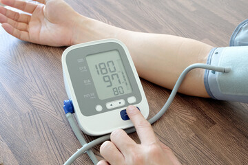 Man checking blood pressure and heart rate with digital sphygmomanometer And the results of measuring high blood pressure are dangerous to health. health concept