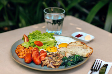 Big American breakfast with two eggs, mushroom, bean, sausages.