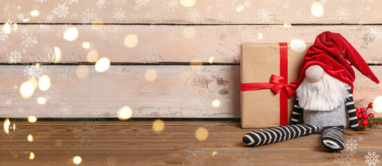Christmas gnome with gift on wooden background with space for text