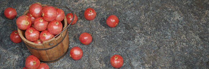pomegranates, juicy fruits in a wooden crate on stone background banner