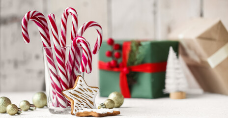 Glass with candy canes, cookies and Christmas decor on table
