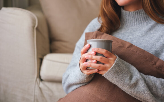 Closeup image of a young woman drinking hot coffee and relaxing at home