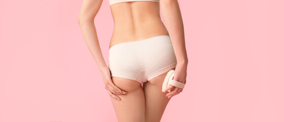 Woman with anti-cellulite massage brush on pink background