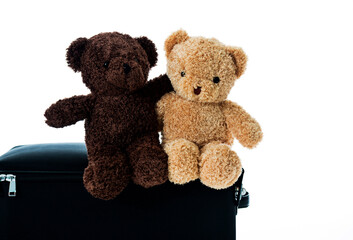 Two embracing teddy bears waiting on a suitcase