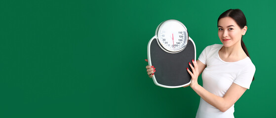 Young Asian woman holding scales on green background with space for text. Weight loss concept