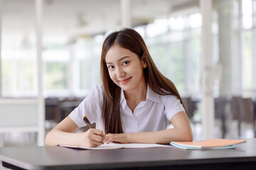 Happy beautiful Asian student girl in uniform working at college.