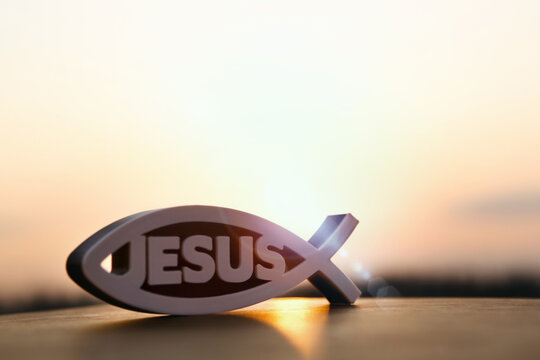 The brightly rising New Year's sunrise and Christian symbol fish figures Ichthys and Jesus
