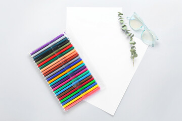 Blank paper sheets with felt-tip pens, eucalyptus branch and eyeglasses on light background