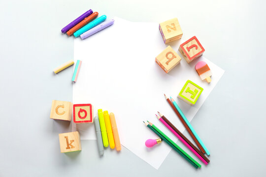 Blank paper sheets with felt-tip pens, pencils and cubes on light background