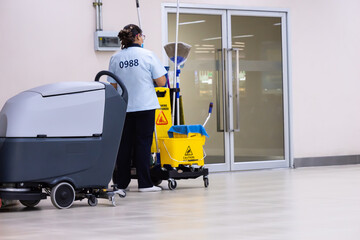 Workers are pushing Janitorail cars inside buildings through cleaning robots, the robot concept is...