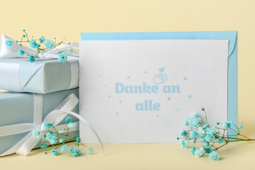 Card with text DANKE AN ALLE, gift boxes and gypsophila flowers on color background, closeup