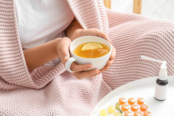 Woman with cup of lemon tea for sore throat at home, closeup
