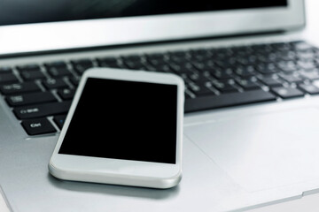 Closeup of smart phone on laptop keyboard
