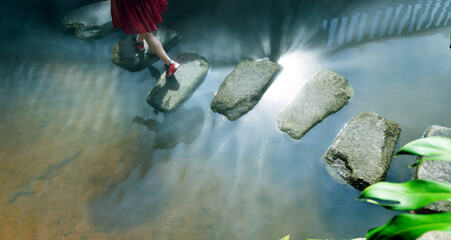 Woman across stepping stones to cross a stream