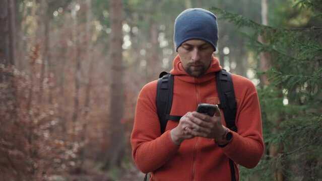 Outdoor mapping in hike. Man hiker uses smartphone to navigate in forest using an application and digital maps. Route for hiking in smart phone. Traveler guides in woods by GPS. Travel and explore. 