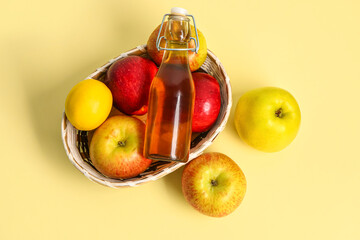 Basket with fruits and bottle of fresh apple juice on color background
