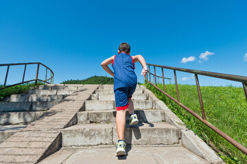 Rear view of young boy running up on steps