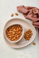 Plate with bowl of almonds on white background