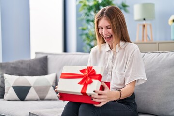 Beautiful woman holding gift smiling and laughing hard out loud because funny crazy joke.