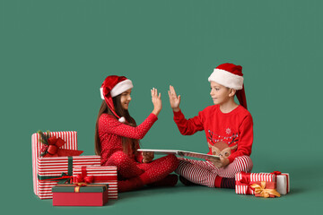 Little children in pajamas with Christmas gifts and book giving each other high-five on green...