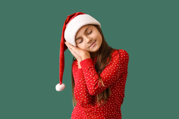 Little girl in Christmas pajamas sleeping on green background