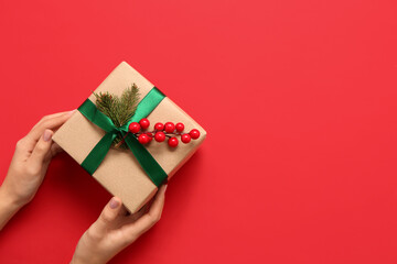 Woman with Christmas gift box on red background, top view
