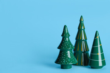 Ceramic Christmas trees on color background