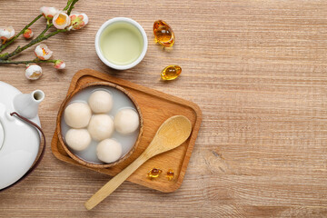Bowl of tangyuan with cup, Chinese decor and sakura on wooden background. Dongzhi Festival