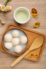 Bowl of tangyuan with cup, Chinese decor and sakura on wooden background. Dongzhi Festival