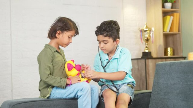Young kids playing with stethoscope checking heartbeat of teddy bear at home - concept of future doctor, childhood lifestyles and togetherness