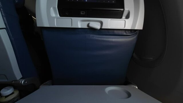 Folding an airplane tray table down and laying it flat. Getting ready to get a meal or snacks