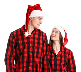 Young couple in Santa hats and pajamas on white background