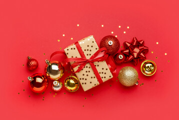Gift box with Christmas balls and bells on red background