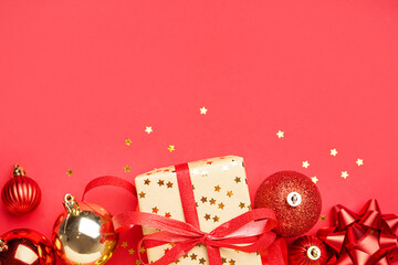 Gift box with Christmas balls and bells on red background