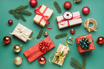 Gift boxes with Christmas balls and fir branches on green background