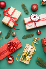 Gift boxes with Christmas balls and fir branches on green background